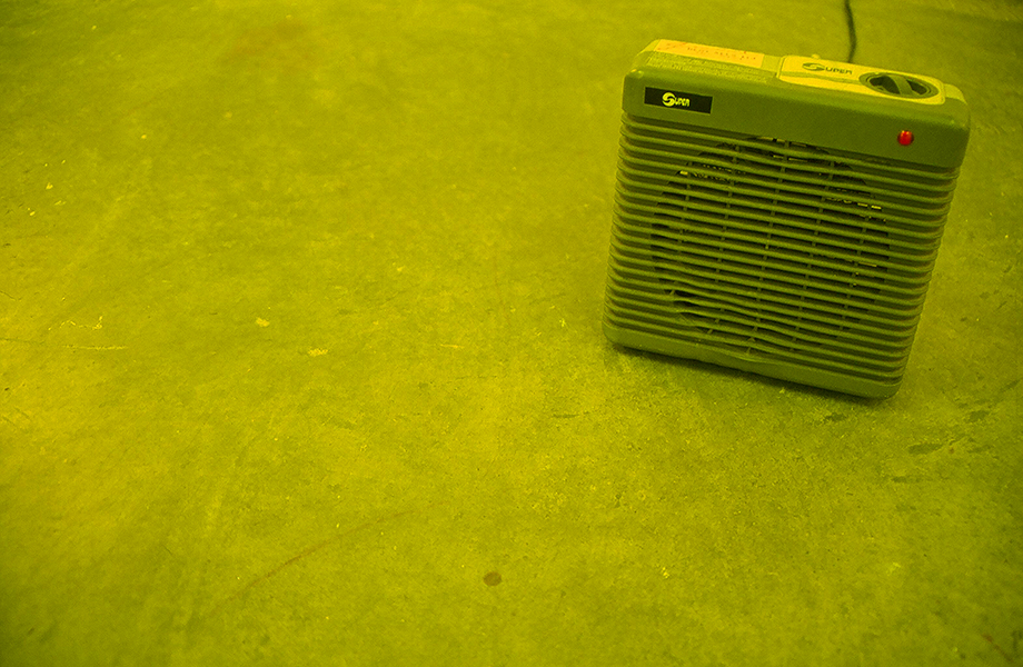 The radiator, image from TOO MUCH IN THE SUN by Kennedy Telford. The lighting in a room is covered in yellow gels and the room is heated to a warm temperature.