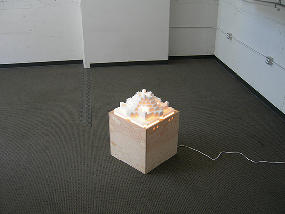 AZIMUTH, a castle-shaped sculpture of sugar cubes resting on a handbuilt wooden box, is lit from within. Work by Kennedy Telford.